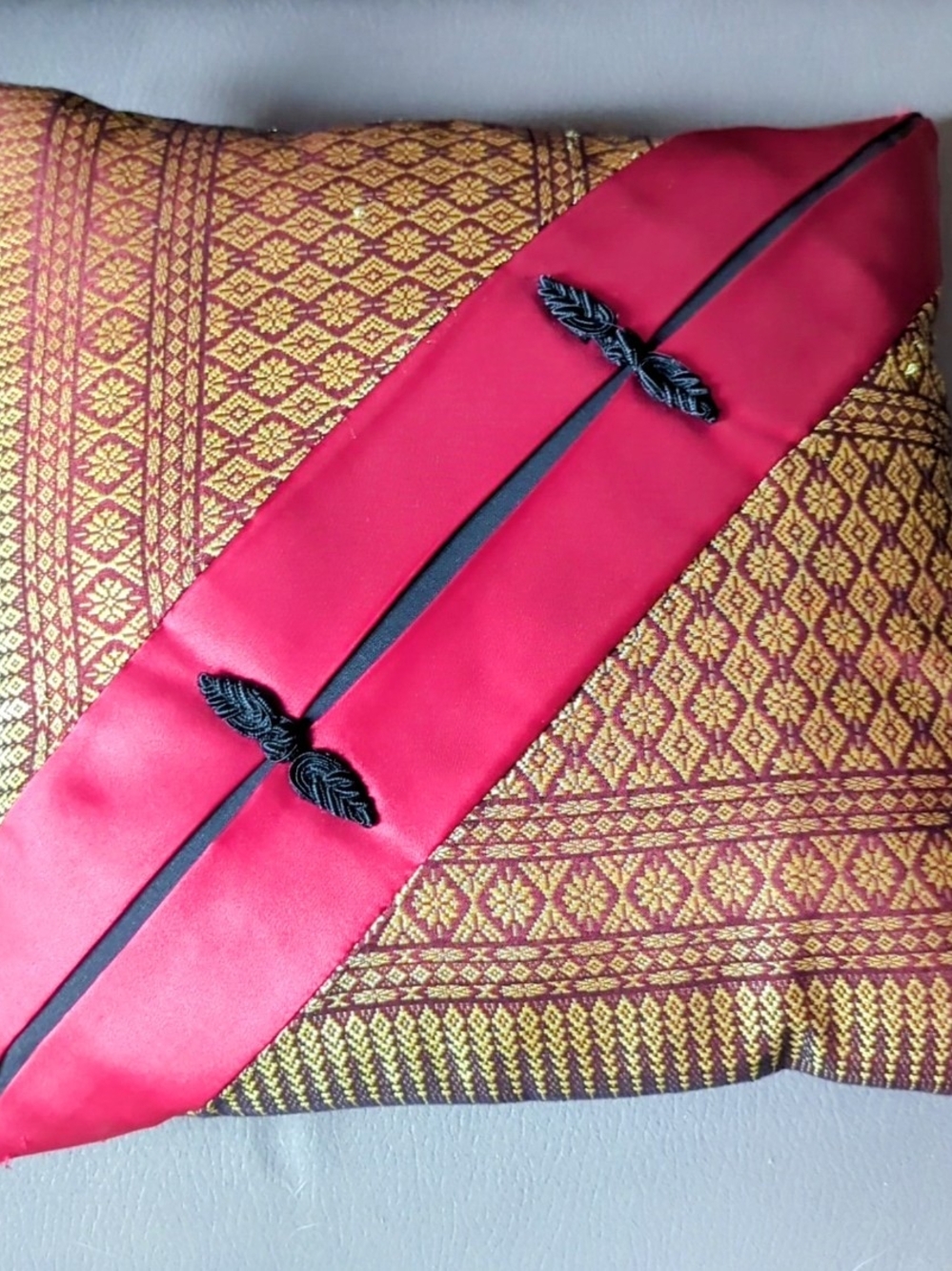This decorative throw pillow features a traditional gold and maroon brocade